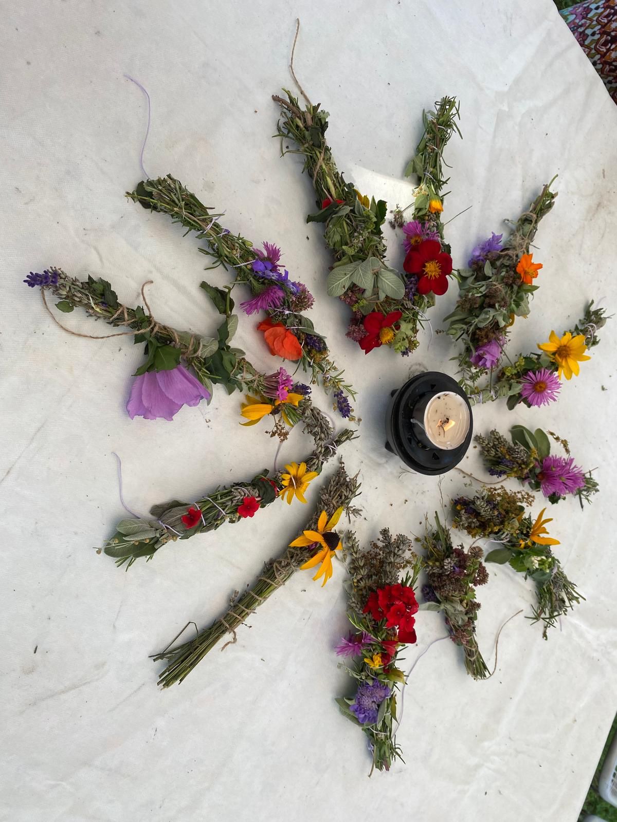 Auf dem weiÃen Tuch liegen im Kreis selbstgemachte KrÃ¤uterbÃ¼ndel.