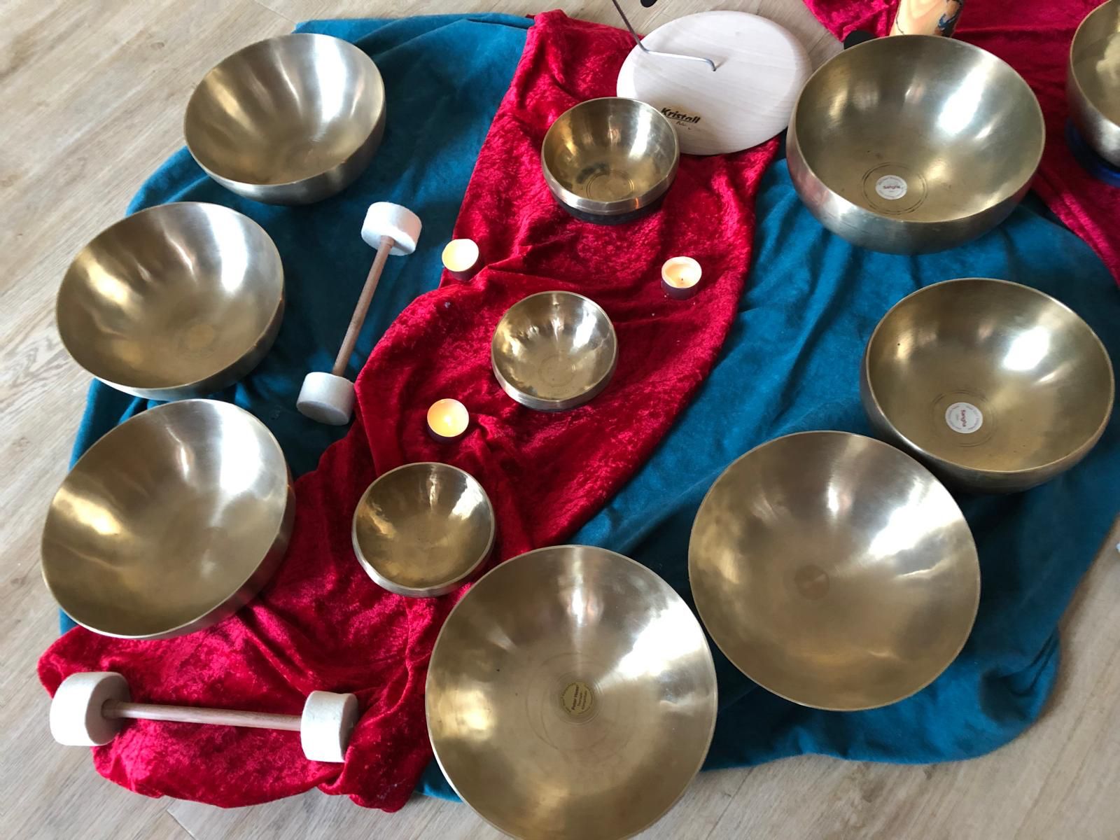Viele klangschalen und schlegeln auf einem roten  und blauen Tuch platziert
