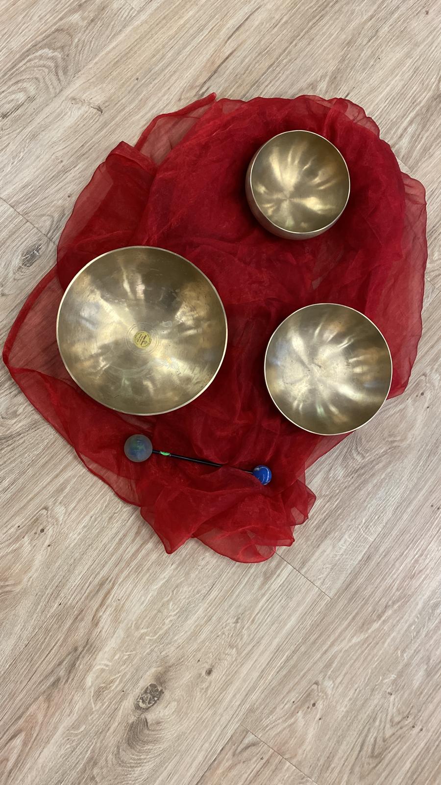3 Klangschale auf ein rotes Tuch mit Schlegel platziert.