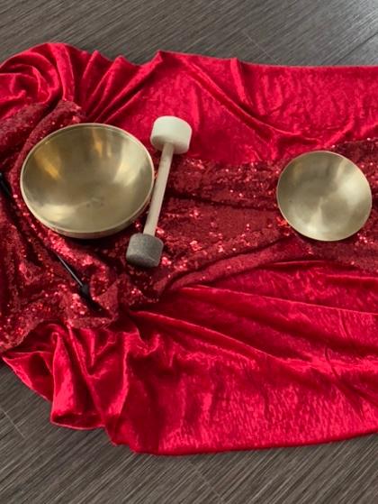 Viele klangschalen und schlegeln auf einem roten  und blauen Tuch platziert